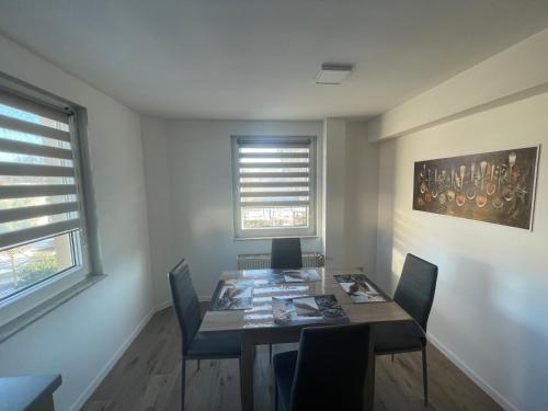 a dining room with a table and chairs and two windows at Ferienwohnung Ulsteraue in Geisa
