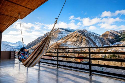 a woman sitting in a hammock overlooking mountains at Old District View Hotel kazbegi in Kazbegi