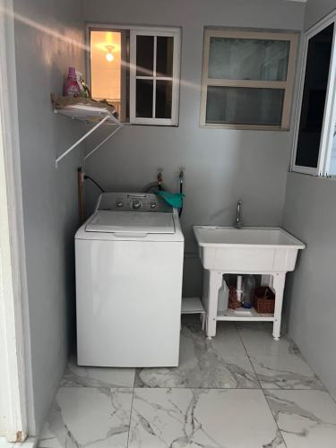 a washing machine in a bathroom with a sink at Op paradise living in Kingston