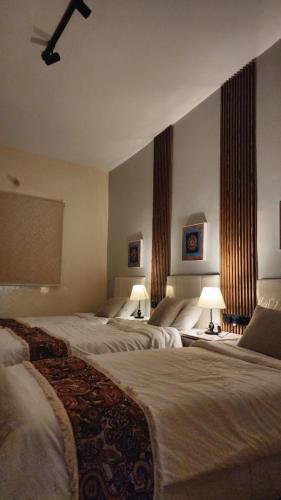 a hotel room with three beds and two lamps at بيت لانا in Abha