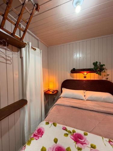 a bedroom with a bed with pink flowers on it at Pousada Nó de Pinho - Kitnet Microcasa in São Joaquim