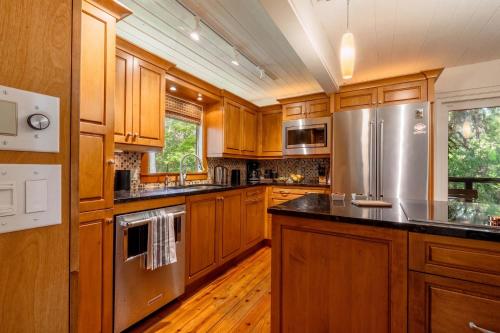 a kitchen with wooden cabinets and a stainless steel refrigerator at TreeTops Spacious Architectural Retreat in Gainesville