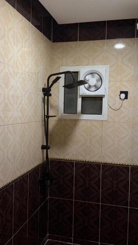 a shower in a tiled bathroom with a fan at شقق عناوين الفخامة in Şāmitah