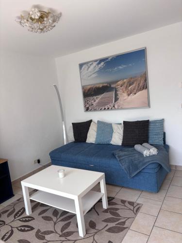 a living room with a blue couch and a table at Strandkorb 115 in Rostock