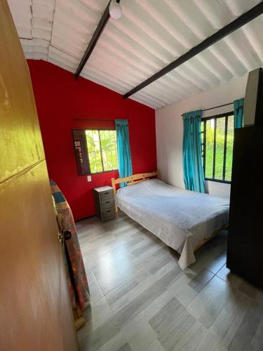 a bedroom with a bed and a red wall at Casa campestre Shalom in Vergara