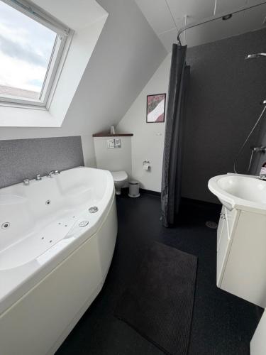 a bathroom with a large white tub and a sink at Kystvejen 40F in Hadsund