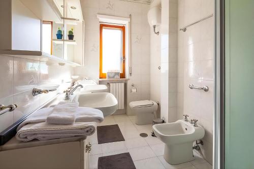 a white bathroom with three sinks and a toilet at Aranci 99 House in Sorrento