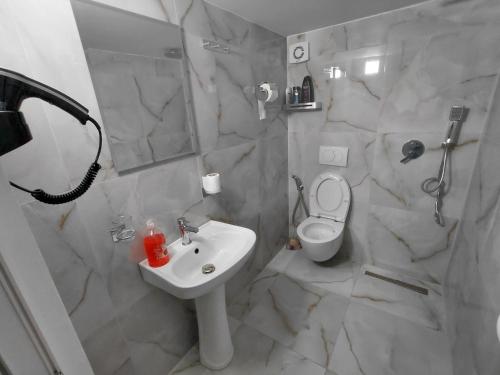 a white bathroom with a sink and a toilet at Sol Apartments in Durrës