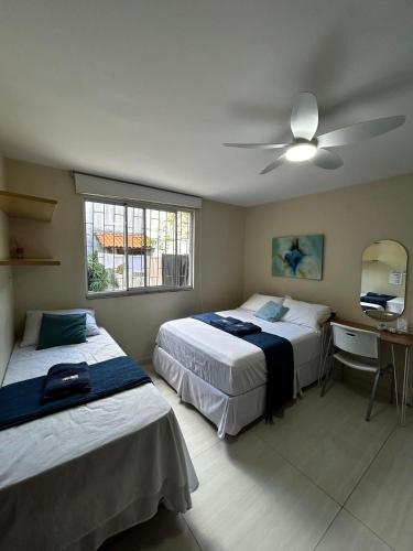 a bedroom with two beds and a ceiling fan at Casa do Loro Hospedagem in Curitiba