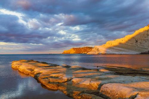 a group of rocks in the water under a cloudy sky at WHITE COAST APARTMENTS - Family Stays and Free Parking in Realmonte
