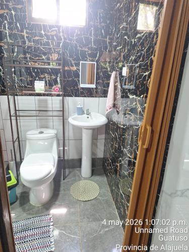 a bathroom with a white toilet and a sink at Sloth House Rio Celeste in Rio Celeste