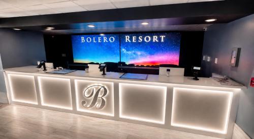 a white reception counter in a room with a large screen at Bolero Resort in Wildwood