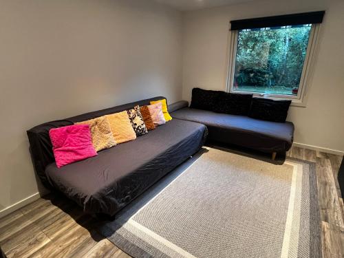 a living room with a black couch with colorful pillows at Modern villa apartment with free parking in Sollentuna