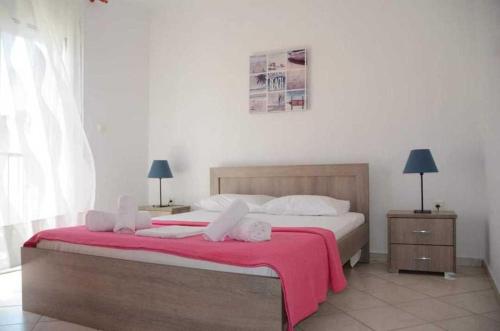 a bedroom with a large bed with a red blanket at Roses RT apartments Skioni I in Nea Skioni
