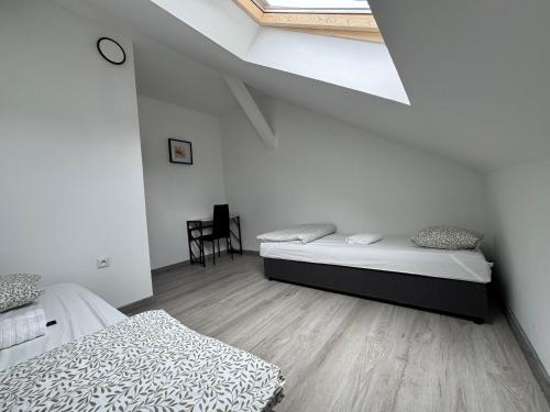 two beds in a white room with a skylight at Air AMBER PEN LOTNISKO parking in Kaszów