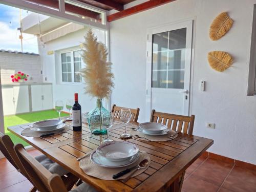 a wooden table with plates and a bottle of wine at Roque`s House A in Telde