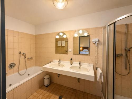 a bathroom with two sinks and a tub and a shower at Hotel Wildpferd Dülmen in Dülmen