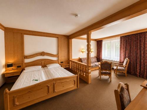 a bedroom with a large wooden bed and a desk at Hotel Wildpferd Dülmen in Dülmen