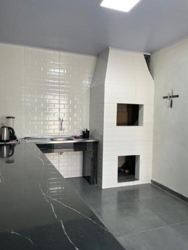 a white kitchen with a sink and a fireplace at Pousada aconchego in Imbituba