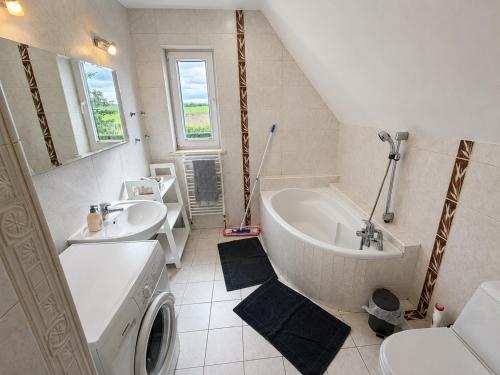 a bathroom with a sink and a tub and a washing machine at Mazurski Dom Sucholaski in Wydminy