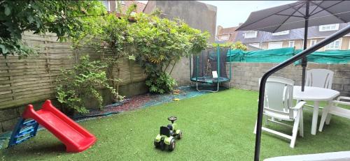 a small backyard with a toy bike on the grass at Escapade Bord de Mer - Terrasse & Parking privé, Plage à 300 m in Le Portel