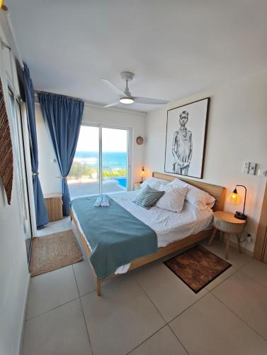 a bedroom with a bed and a large window at Villa Dérimbeault in Oyster Pond