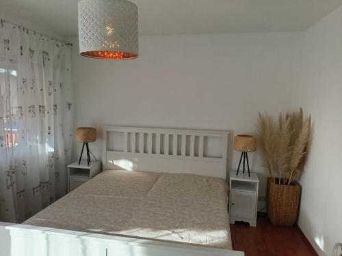 a white bedroom with a bed and two lamps at Gemütliche Ferienwohnung in Philippsburg