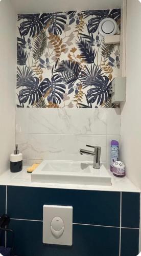 a white sink in a bathroom with a patterned wall at Bénodet appartement 100m de la plage thalasso 2chambres parking privé internet avec box in Bénodet