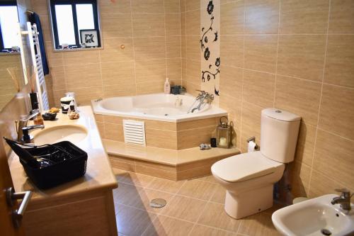 a bathroom with a tub and a toilet and a sink at Casa da Aldeia in Penafiel