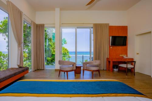 a bedroom with a bed and a desk with a view of the ocean at Iconic Polhena in Matara