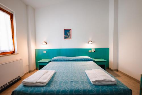 a bedroom with a green bed and two tables at Villaggio Torre Ruffa Robinson in Capo Vaticano