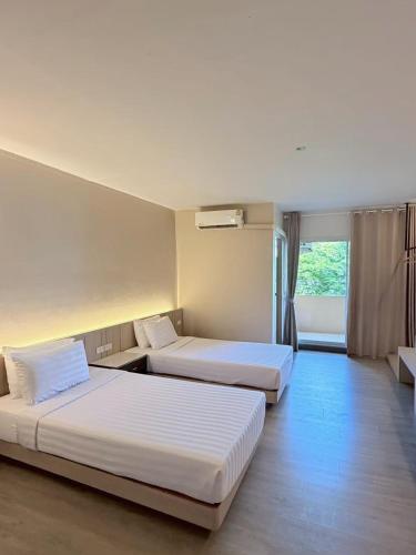 a hotel room with two beds and a window at Smile Bed Hotel in Sathani Khlong Rian