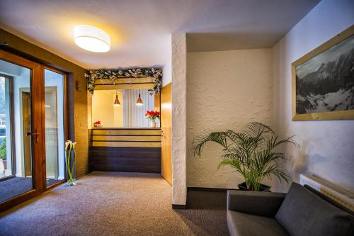 a hallway with a couch and a door with a plant at Penzion Flores in Demanovska Dolina