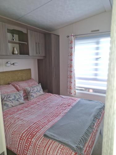 a bedroom with a bed with a red blanket and a window at Ascot at Lochlands in Forfar