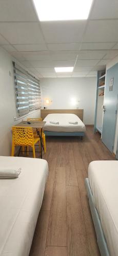 a room with two beds and a table and a bed at Hôtel Duchesse Anne in Lourdes