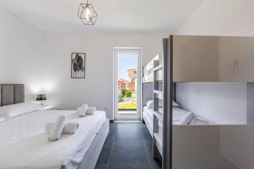 a white bedroom with two beds and a window at Crystal Beach Rooms by PS in Durrës