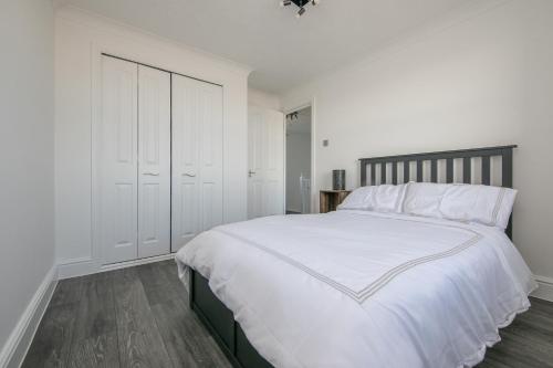 a white bedroom with a large bed with white sheets at Seaview in Clacton-on-Sea