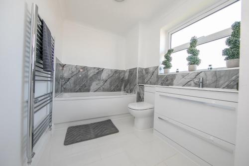 a white bathroom with a tub and a toilet and a window at Seaview in Clacton-on-Sea