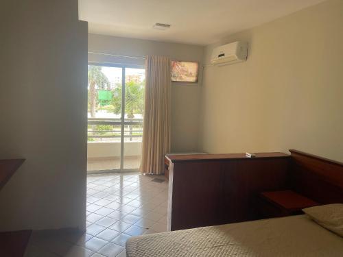 a bedroom with a bed and a desk and a window at Eldorado Flat Service Host Hub | Localização Top em frente ao Clube Privé in Caldas Novas