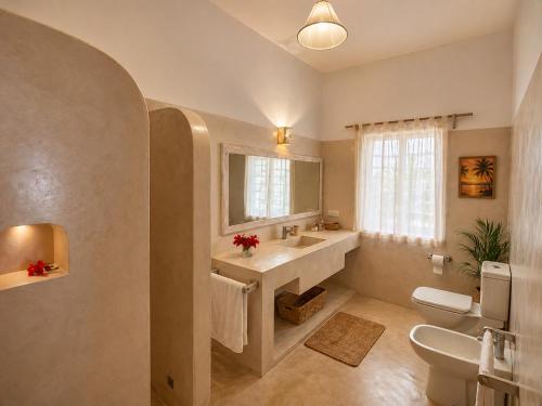 a bathroom with a sink and a toilet and a window at Blue Diamond Villa Watamu in Watamu