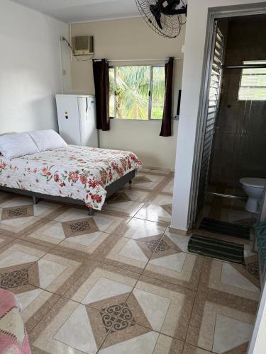 a bedroom with a bed and a bathroom with a window at Recanto dos Amigos Suítes CANTÃO DO INDAIA in Bertioga