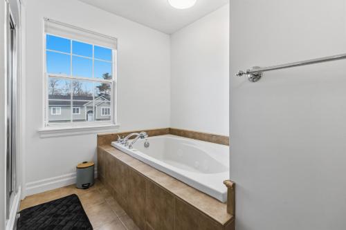 a bathroom with a tub and a window at Spacious 4BR Family Retreat w- Game Room 10p in Dieppe