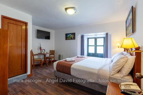 a bedroom with a bed and a table with a phone at Hotel Amerinka in Cusco