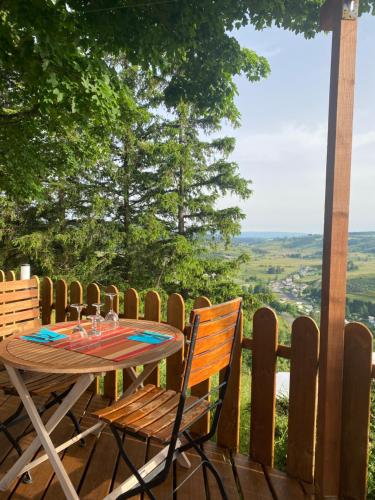a table and chairs on a wooden deck with a view at La Bastide en Margeride in Châteauneuf-de-Randon