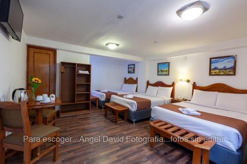 a hotel room with two beds and a desk at Hotel Amerinka in Cusco