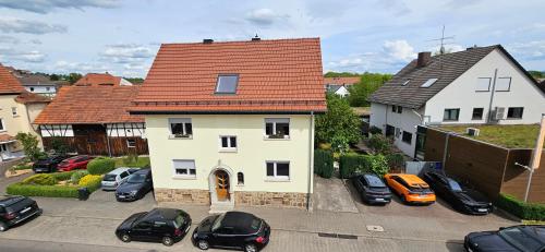 a white house with a red roof and parked cars at Fewo Fulda Neuenberg in Fulda