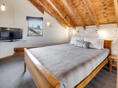 a bedroom with a bed and a flat screen tv at Shining Star Beachfront Accommodation in Hokitika
