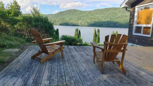 two chairs on a deck with a view of a lake at Chalet l'Apero in Val-des-Bois