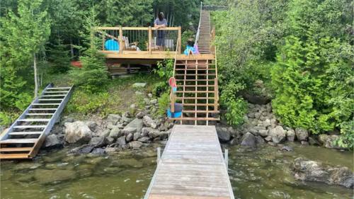 a wooden bridge over a river with people on it at Chalet l'Apero in Val-des-Bois