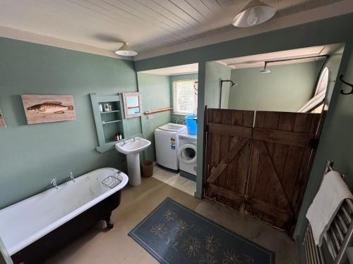 a bathroom with a tub and a toilet and a sink at The Bach - beachfront in Waimarama